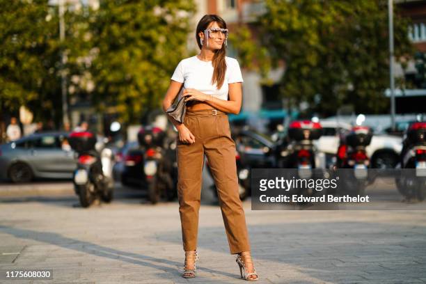 Carlotta Rubaltelli wears fringed and glitter glasses, a white cropped t-shirt, a bag, brown pants, shoes, outside the Alberta Ferretti show during...