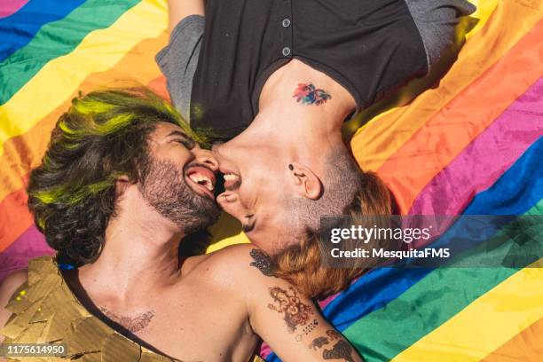 homosexuelle paar sonnenbaden auf der regenbogenflagge liegend - rainbow kiss stock-fotos und bilder