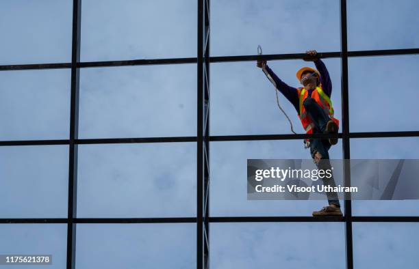 construction worker wearing safety harness and safety line working on roof. - safety harness stock pictures, royalty-free photos & images