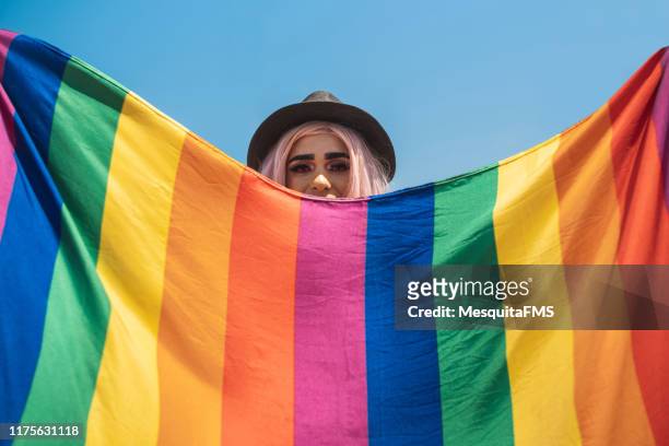 drag queen versteckt sich hinter der regenbogenflagge - pride lgbtqi veranstaltung stock-fotos und bilder