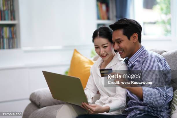 young married couples cheerful using laptop and credit card to shopping online - paid search stock pictures, royalty-free photos & images