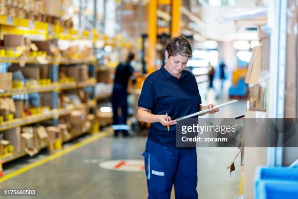 woman checking packages on warehouse racks - arranging products stock pictures, royalty-free photos & images