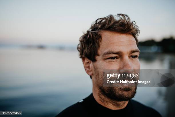 a fit mature sportsman with wetsuit standing outdoors on beach, a copy space. - waterproof photos et images de collection