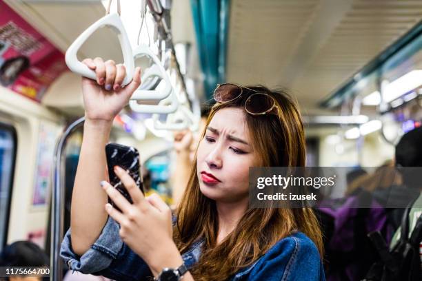 displeased woman using phone in subway train - underground train stock pictures, royalty-free photos & images