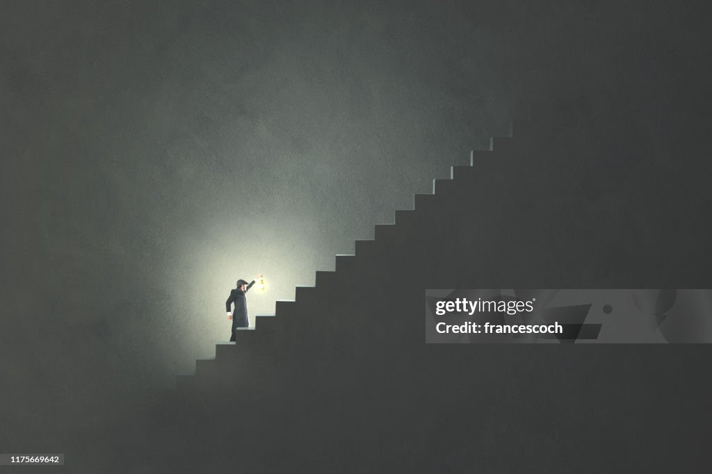 Mann mit Lampe steigt Treppe in der Dunkelheit