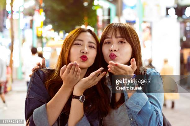 female friends blowing kisses on city street - blowing a kiss stock pictures, royalty-free photos & images