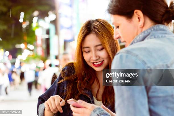 smiling woman assisting tourist using mobile phone - tourist asking stock pictures, royalty-free photos & images