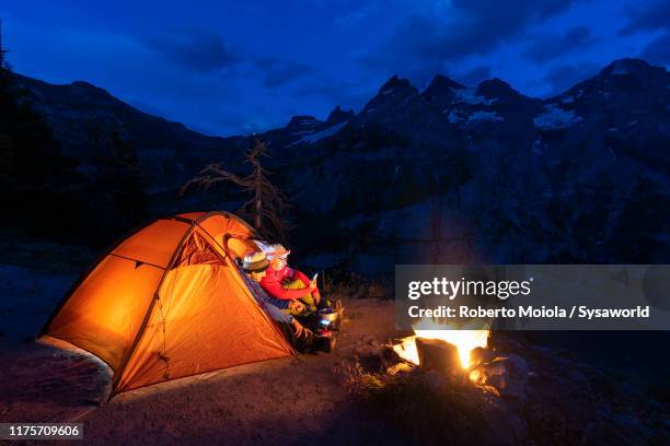 hikers in tent by the campfire, oeschinensee, bernese oberland, switzerland - hot latin nights stock pictures, royalty-free photos & images