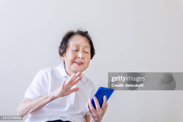 grandmother having video chat on smart phone - asian granny pics stock pictures, royalty-free photos & images