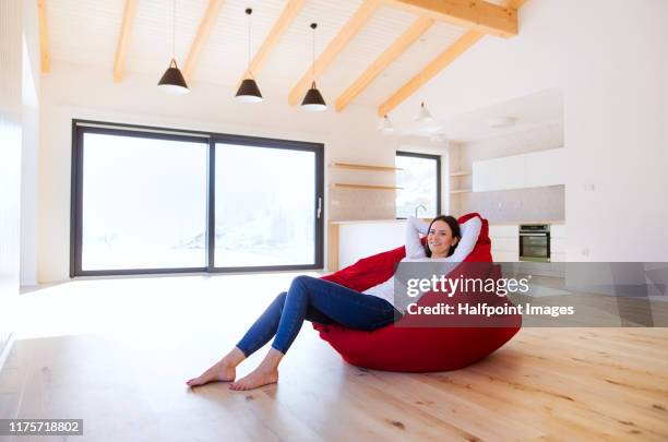 young woman sitting on a bean bag in living room in a new home, resting. - ビーズソファ ストックフォトと画像