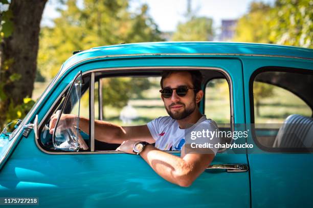 man siting in vintage car on the road - vintage car stock pictures, royalty-free photos & images
