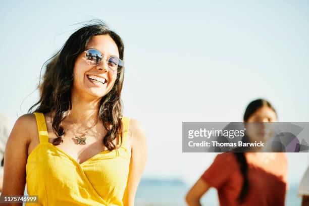 smiling woman hanging out with sister during family beach party on summer afternoon - yellow dress stock pictures, royalty-free photos & images