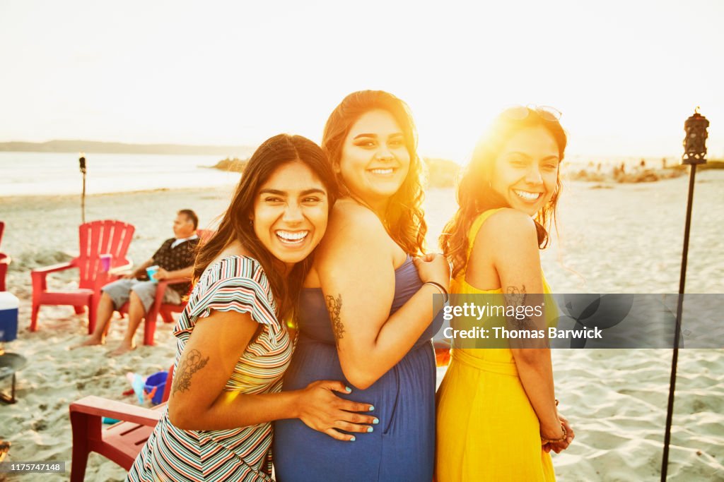 Three laughing sisters on beach during family party at sunset