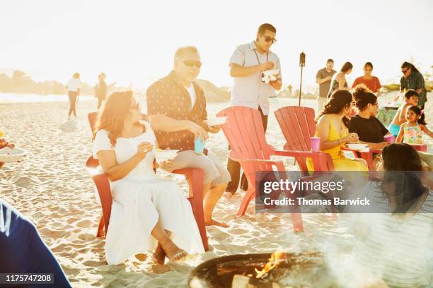 grandparents sitting together on beach chair during beach party with family - beach party stock pictures, royalty-free photos & images