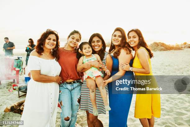 Portrait of smiling mother adult daughters and granddaughter on beach during family party
