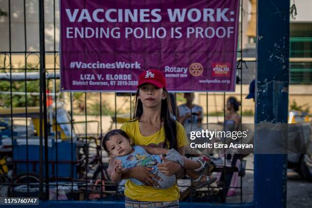 Parent brings her child to be administered an oral polio vaccine, during a mass vaccination campaign to combat the resurgence of the polio virus, at...