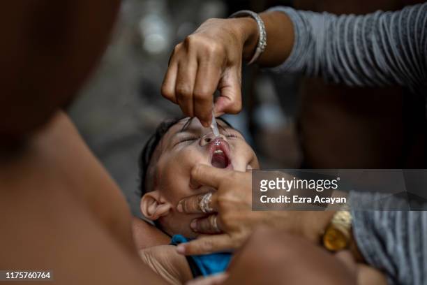 Community health worker administers an oral polio vaccine to a child, during a mass vaccination campaign to combat the resurgence of the polio virus,...