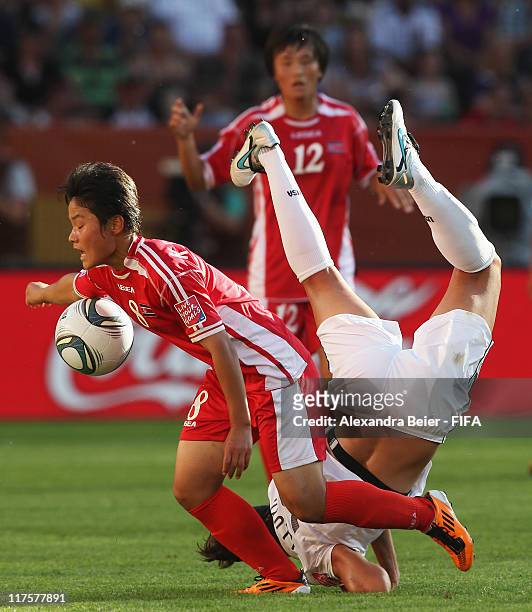 Carli Lloyd of USA falls after fighting for the ball with Kim Su Gyong of Korea DPR during the FIFA Women's World Cup 2011 Group C match on June 28,...