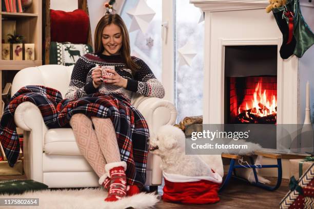 young woman drinking hot chocolate by the fireplace - hairy-girl stock pictures, royalty-free photos & images