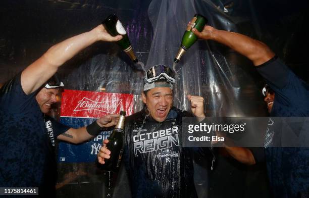 Masahiro Tanaka of the New York Yankees is doused with champagne by teammates Austin Romine and Cameron Maybin after the New York Yankees clinched...