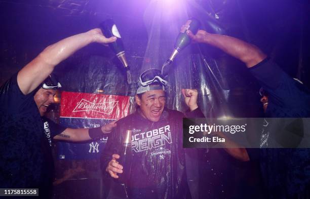 Masahiro Tanaka of the New York Yankees is doused with champagne by teammates Austin Romine and Cameron Maybin after the New York Yankees clinched...