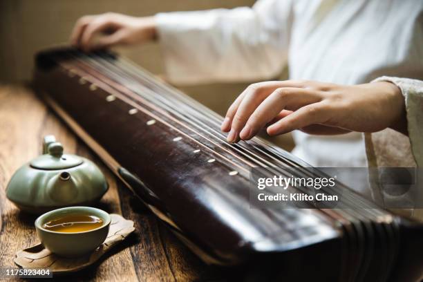 asian woman playing the guqin (an ancient chinese string musical instrument) - chinese instrument stock-fotos und bilder
