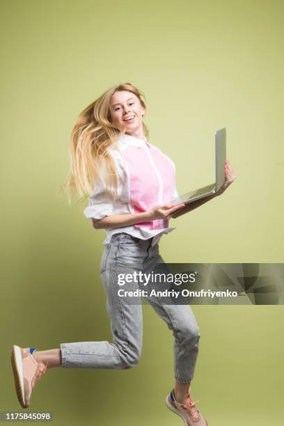 young adult female jumping for joy - laptop colored background stock pictures, royalty-free photos & images