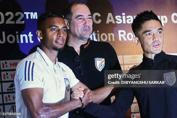 Bangladesh' football captain Jamal Bhuyan shakes hands with Indian captain Sunil Chhetri as India's coach Igor Stimac looks on during a press...