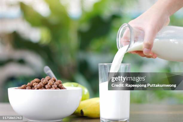 pouring milk into a glass of nutritious and delicious chocolate cereals - chocolate milk splash stock pictures, royalty-free photos & images