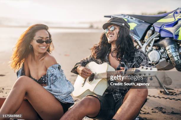 ragazzo che suona la chitarra acustica alla sua ragazza sulla spiaggia - mare moto foto e immagini stock