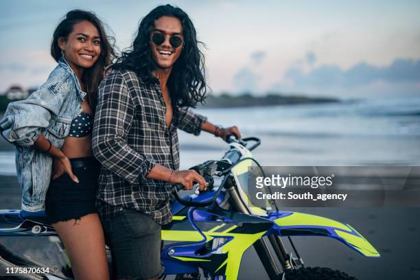 coppia felice in sella in moto in mare al tramonto - mare moto foto e immagini stock