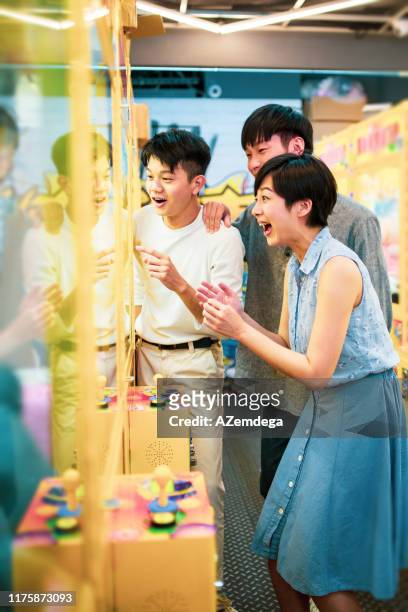 friends playing arcade claw machine - claw machine stock pictures, royalty-free photos & images