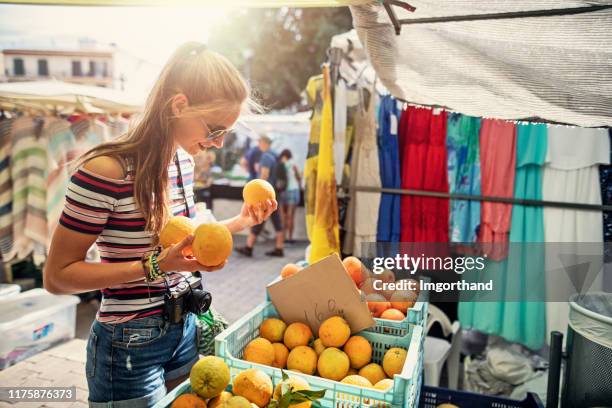 teenage girl buying fresh organic oranges at farmer's market - street market stock pictures, royalty-free photos & images