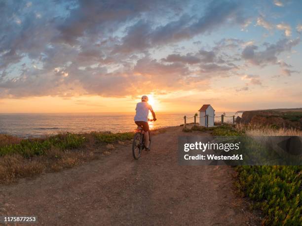 portugal, alentejo, senior man on e-bike at sunset - alentejo stockfoto's en -beelden