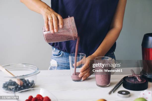 woman pouring smoothie into glasses - smoothie bildbanksfoton och bilder
