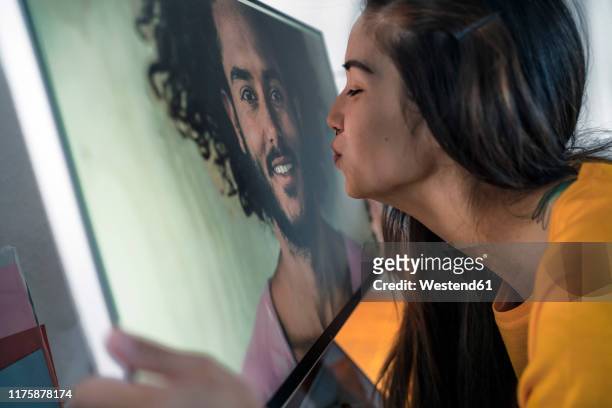 young woman kissing man on computer screen - långdistansförhållande bildbanksfoton och bilder