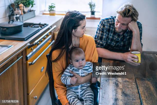 serious family with baby sitting at kitchen table at home - millennial generation stock-fotos und bilder