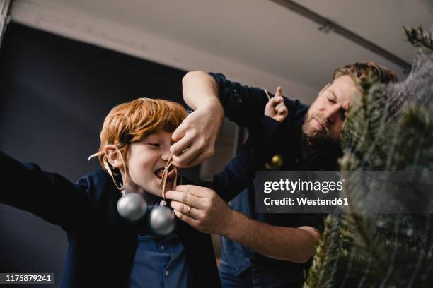 father decorating his son at christmas time - christmas humor stock-fotos und bilder