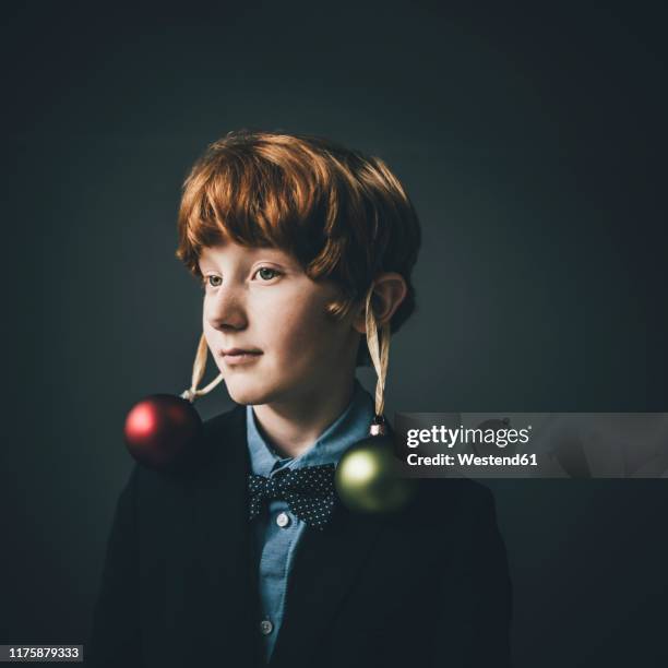 portrait of redheaded boy wearing bow tie and christmas baubles - naughty christmas ornaments stock pictures, royalty-free photos & images