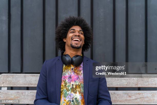 laughing stylish man sitting on a bench - multi colored coat stock pictures, royalty-free photos & images