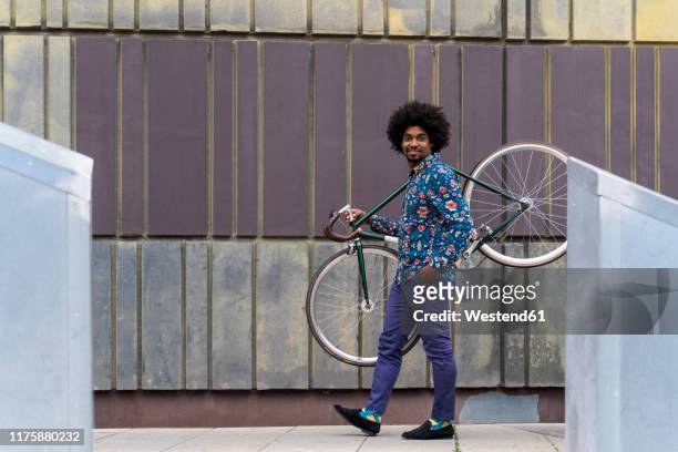 stylish man carrying bicycle in the city - menswear stock pictures, royalty-free photos & images
