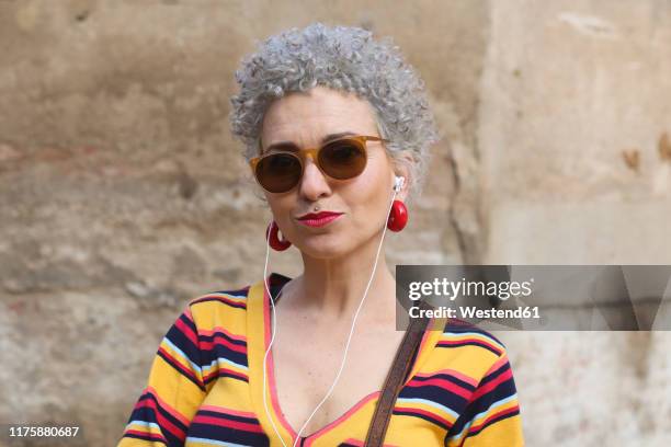 portrait of pierced mature woman with ear phones - curly red hair glasses stock pictures, royalty-free photos & images