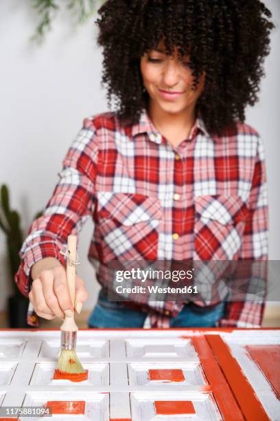 woman painting furniture with brush at home - plaid shirt stock-fotos und bilder