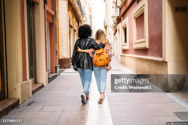 rear view of multicultural women walking in the city, almeria, spain - femmes de dos enlacée photos et images de collection