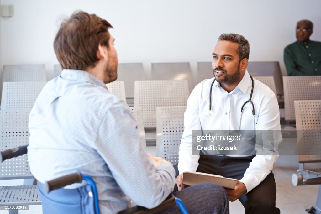 Médico discutiendo con pacientes varones discapacitados