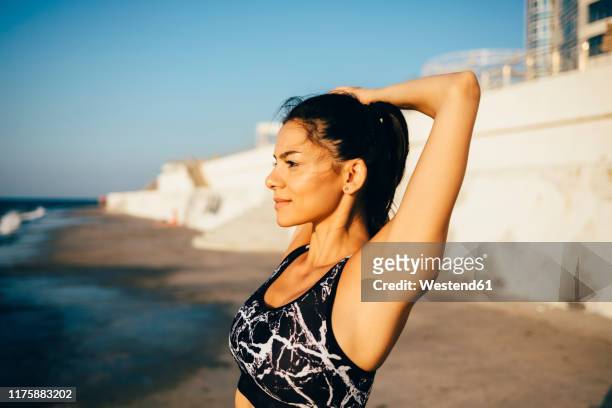 woman during workout, stretching arm on the beach - armpit imagens e fotografias de stock