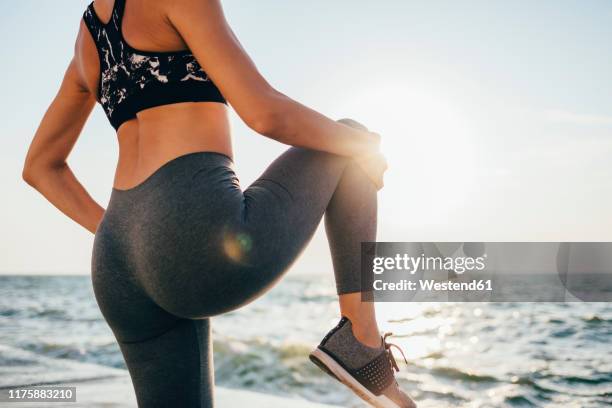 rear view of a woman stretching her leg on a pier - legging stock-fotos und bilder