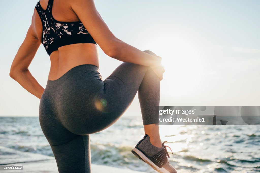 Rear view of a woman stretching her leg on a pier