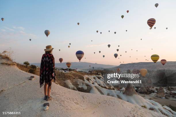 young woman and hot air balloons in the evening, goreme, cappadocia, turkey - wow foto e immagini stock