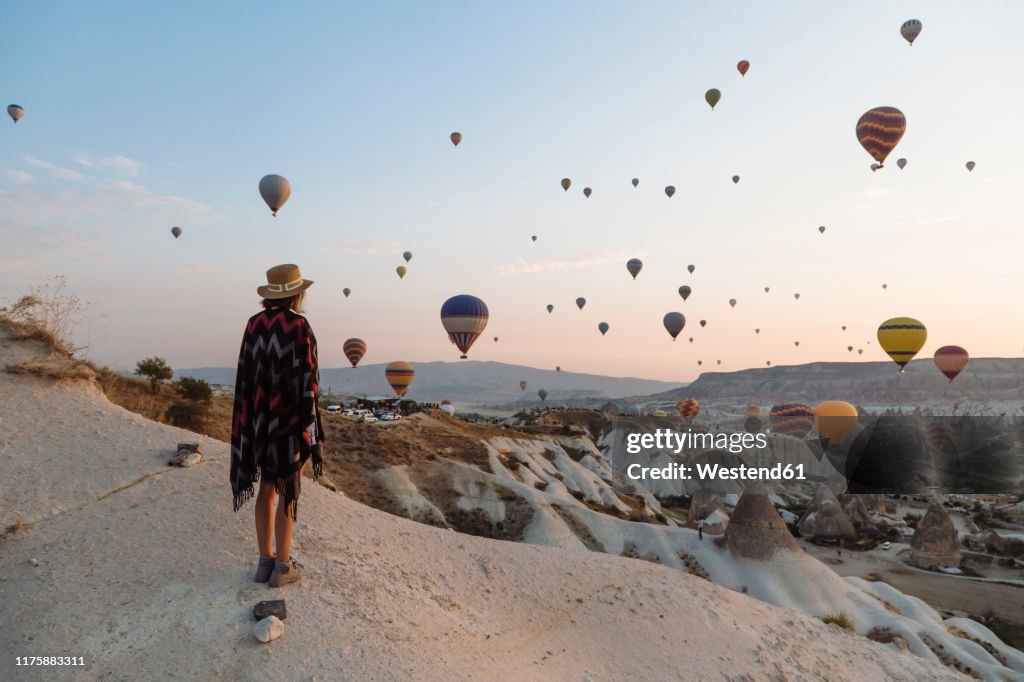 Young woman and hot air balloons in the evening, Goreme, Cappadocia, Turkey